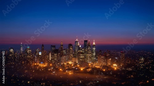 Manhattan Skyline Silhouette Transitioning from Sunset to Night with Twinkling City Lights.