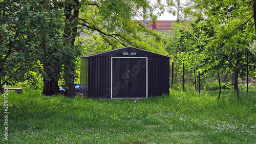 Konstfotografi Modern anthracite metal garden shed nestled among lush green trees in a backyard