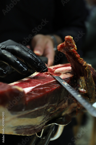 Foto profesional del corte de jamón ibérico cortando loncha de jamón con cuchillo y g