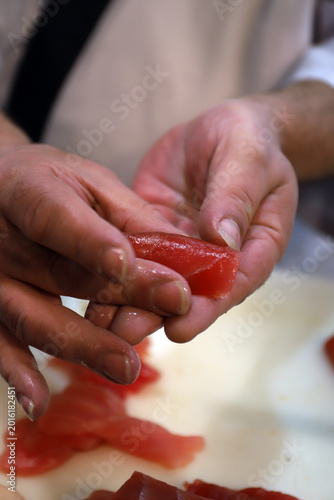 Foto cocinero profesional elaborando un rollito de  sushi de atún rojo y arroz