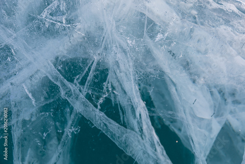 Close up of transparent blue ice with natural cracks and frozen bubbles on Lake Baikal in winter, Russia. Cold seasonal background texture for nature and travel themes