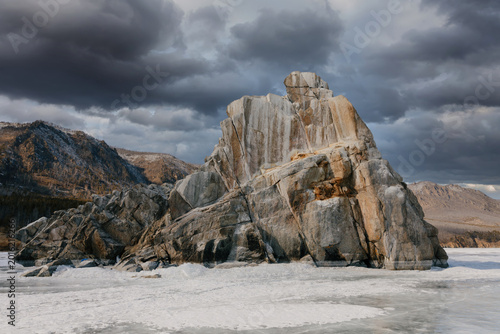Fényképezés Massive granite rock formation rises above the frozen surface of Lake Baikal in