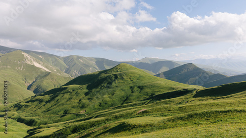 Canvas-taulu Wide panoramic view of rolling green mountain ridges and valleys under dramatic