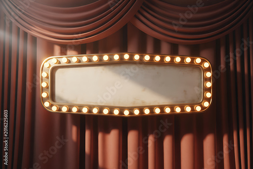 A golden marquee sign with lights is mounted on a red curtain backdrop indoors.