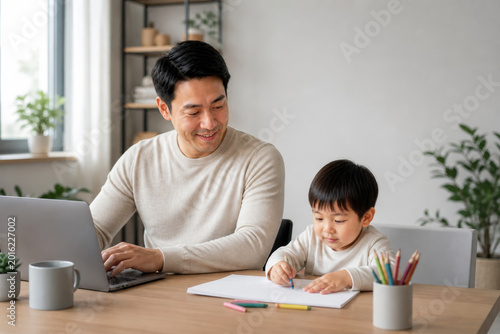 Father working on laptop while child drawing at home desk