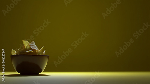 Bowl of potato chips in spotlight with junk food fast food ready to eat appetizer