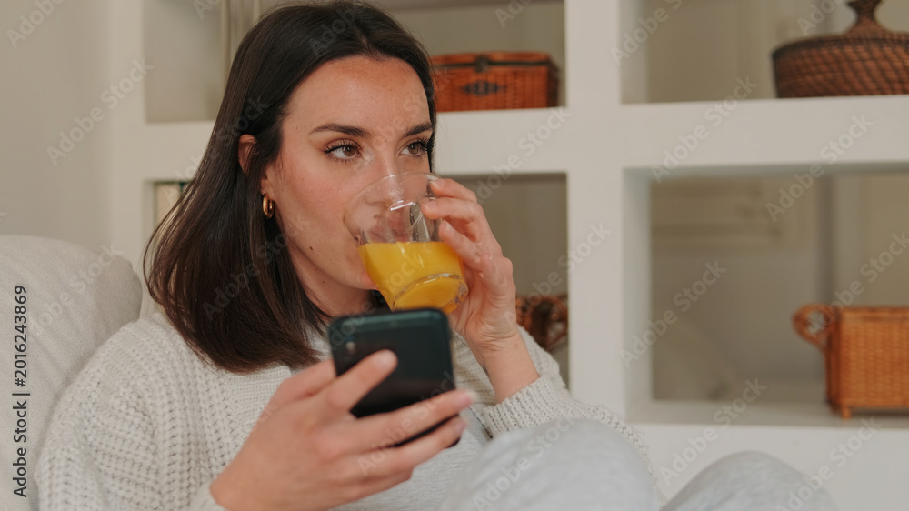 Fototapeta premium Woman Relaxing At Home With Orange Juice And Phone