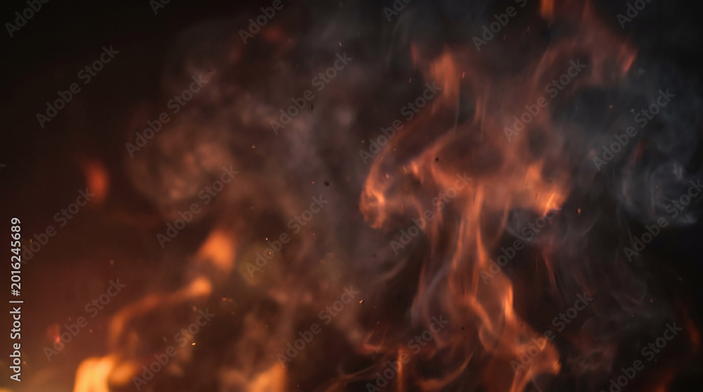 Fototapeta premium A close-up view of burning flames and smoke in darkness.