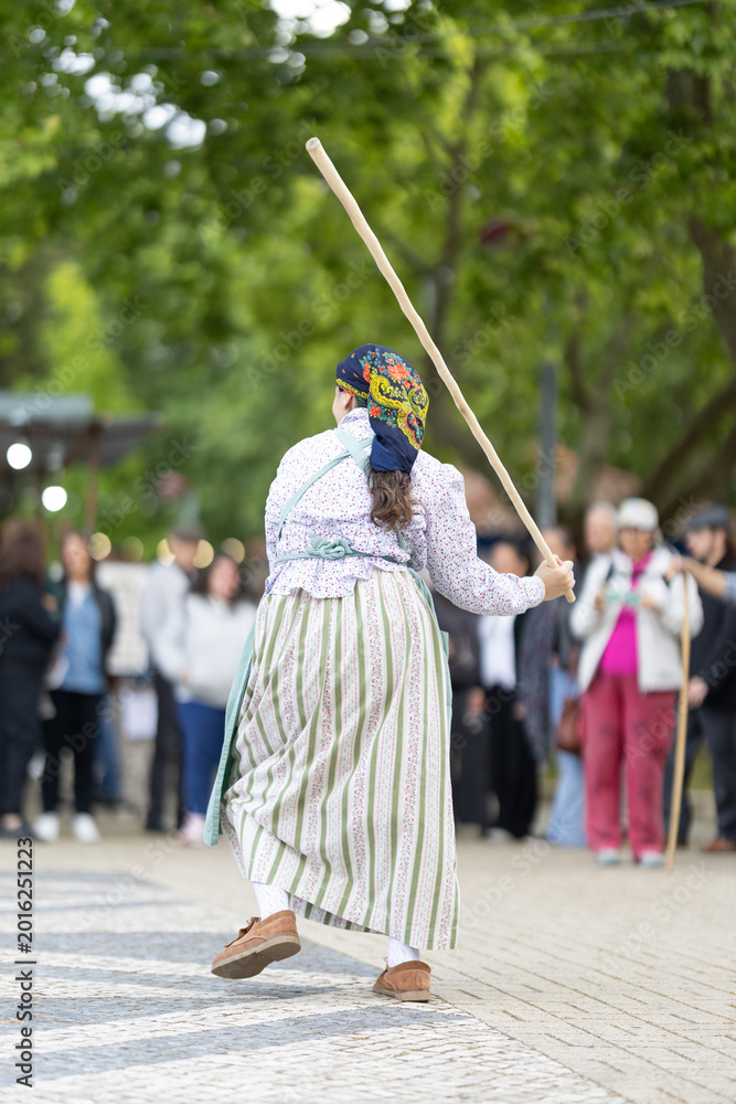 Naklejka premium Dancer performs traditional routine with stick during outdoor event near crowd in the afternoon light