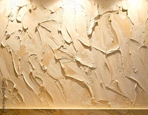 Abstract textured wall surface illuminated by warm light, showcasing intricate plasterwork and unique decorative patterns for modern interior design