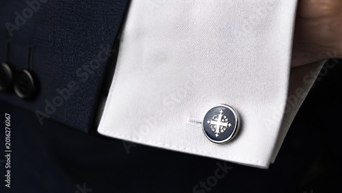 Extreme close-up of a sophisticated cufflink on a crisp white shirt cuff.