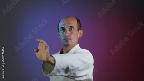 A young athlete practices punches and blocks with his hands against a multi-colored background with flashing lights.
