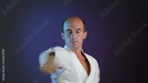 A young athlete performs punches and blocks with his hands against a multi-colored background with flashing lights