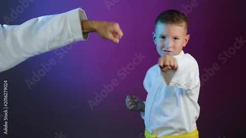 Young athlete and little boy athlete performing hand strikes on multi-colored background with flashing light