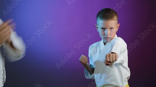 Young athlete and little boy athlete throw punches on colorful background with flashing light