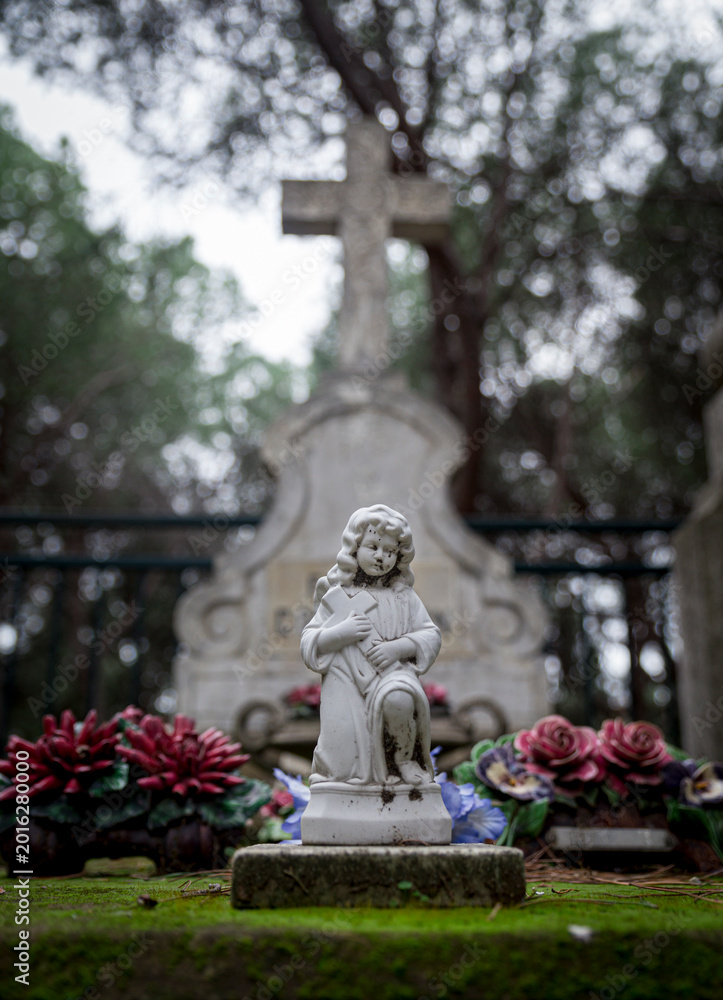 Obraz premium Small religious statue, memorial flowers in Marseille cemetery