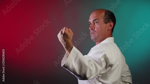A young athlete punches and blocks with his hands against a multi-colored background with flashing red and green lights