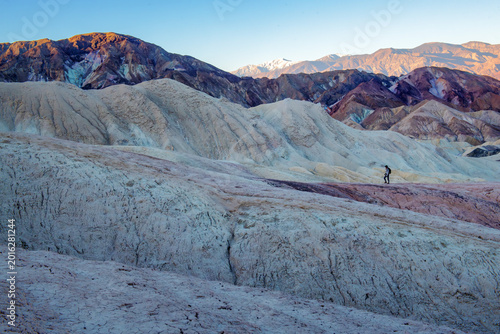 Hiker exploring the badlands of Death Valley at sunrise.