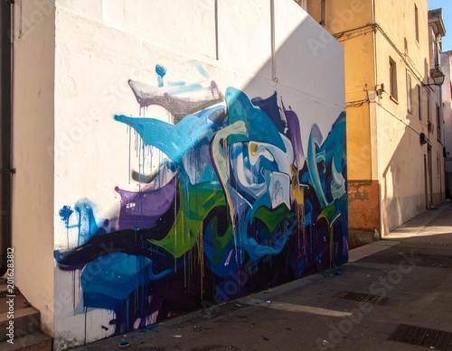Vibrant abstract graffiti mural with striking blue and purple hues adorning a sun-drenched urban wall