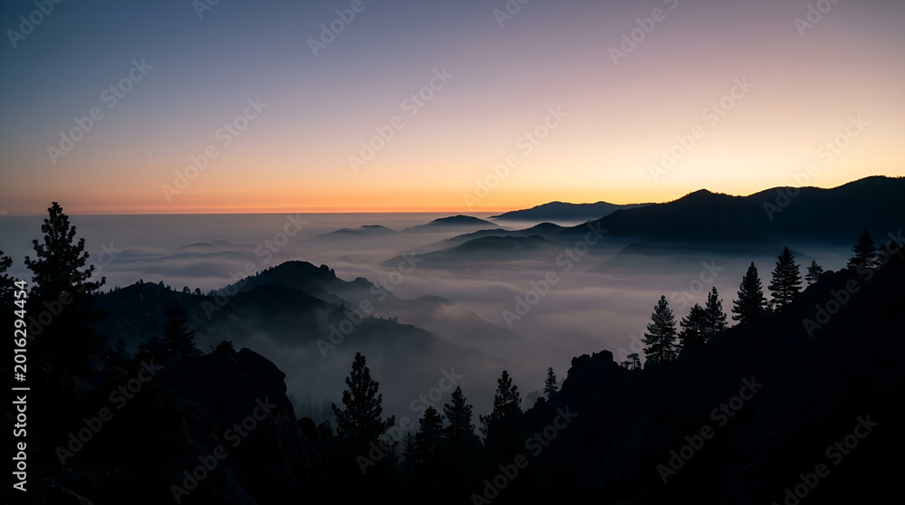 Obraz premium Stunning sunset view over mountain ranges covered by sea of clouds.