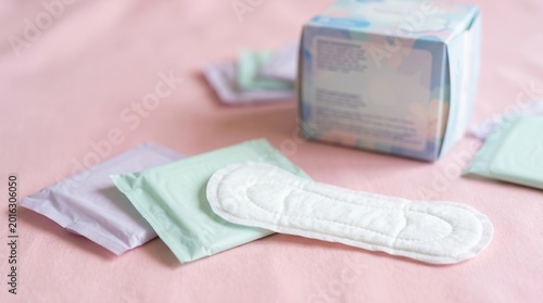 Sanitary pads and feminine hygiene products on soft pink background with pastel packaging and wellness concept