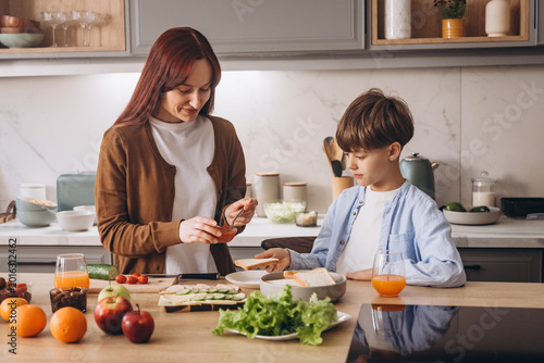 Mother with son cooks sandwiches for breakfast in kitchen
