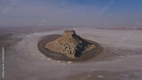Aerial View of Isolated Rock Formation Rising from Arid Desert Basin Under Clear Sky