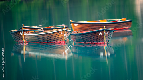 Εκτύπωση καμβά Wooden rowboats with oars reflecting on still turquoise alpine lake