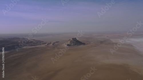 Ancient stone fortress stands resilient atop desert plateau under vast twilight sky