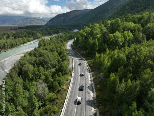 Aerial view of vehicles traveling along winding mountain road beside river