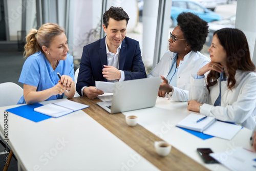 Photos Mid adult businessman having a meeting with group of doctors in hospital