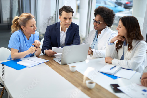 Mid adult businessman having a meeting with group of doctors in hospital