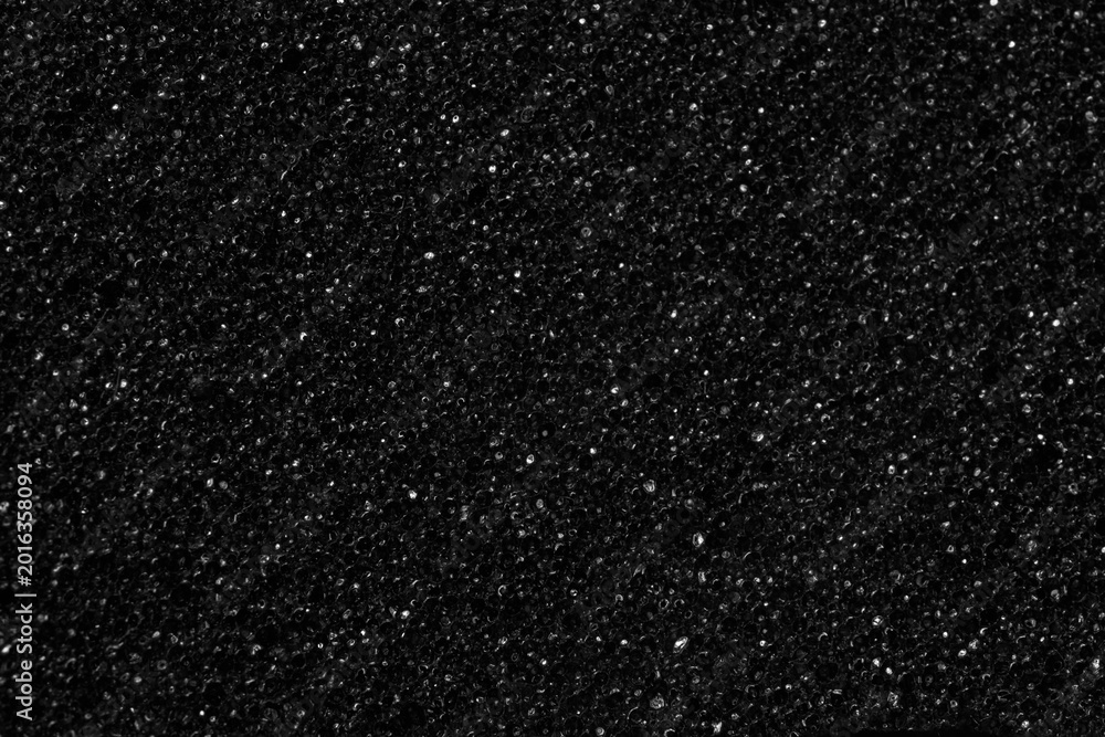 Fototapeta premium Black foam sponge material with iridescent highlights, similar to space