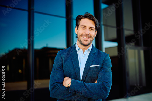 Quadro su tela Young professional man with a confident smile and crossed arms standing in front