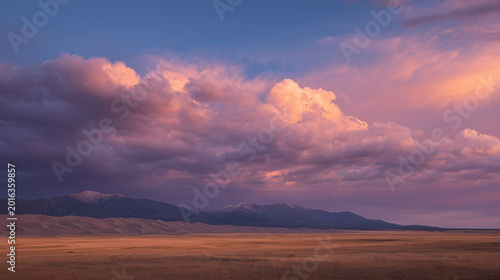Landscape view of a field with mountains in the distance under a colorful cloudy sky at sunset time