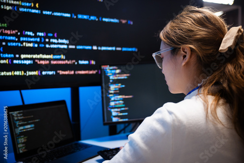 Focused Asian female programmer coding at her office desk