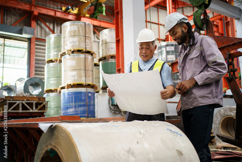 Factory workers inspecting industrial material and construction plans