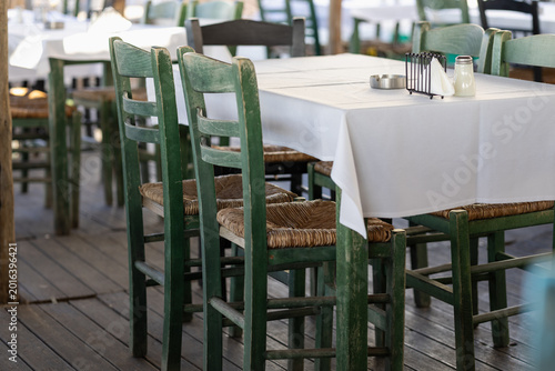 Konstfotografi traditional greek tavern setting with green wooden chairs and woven straw seats