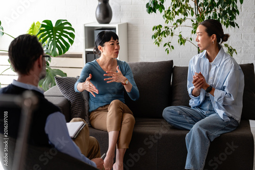 Group therapy session with diverse adults talking and listening in a supportive environment, sharing emotions and experiences during a mental health counseling meeting
