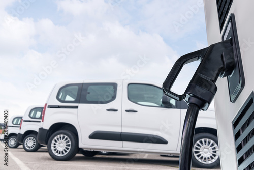 Electric vehicles charging station on a background of a row of vans. Green transportation concept