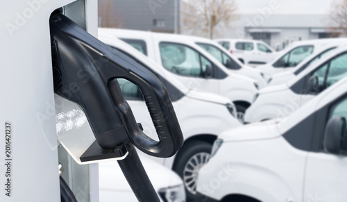 Electric vehicles charging station on a background of a row of vans. Green transportation concept