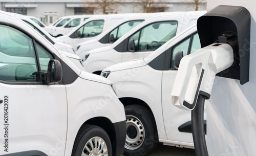 Electric vehicles charging station on a background of a row of vans. Green transportation concept