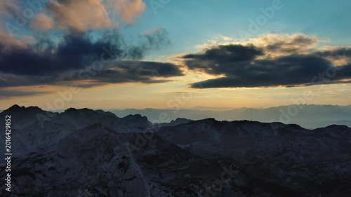 Sun setting over mountain with dramatic clouds. Beautiful evening sky at sunset, aerial view 4k