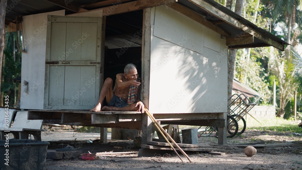 Fototapeta premium Old asian man relaxing at home in rural village, peaceful simple lifestyle