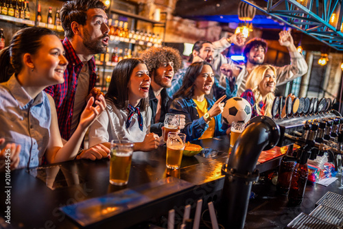 Schilderij op canvas Diverse friends cheering for soccer match with beer at bar counter