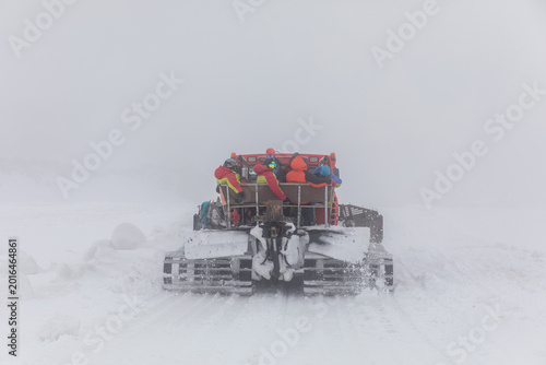 Photography Rear view of a snowcat transporting climbers through a blizzard and low visibili