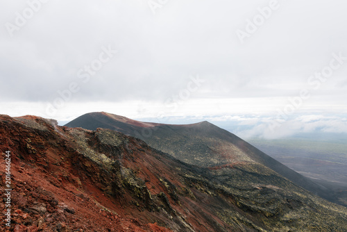 Canvas-taulu Wide landscape view of rugged volcanic ridge with red scoria and dark lava field