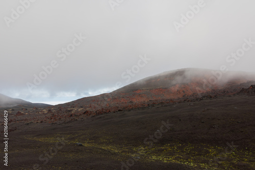 Canvas-taulu Wide view of Tolbachinsky Dol volcanic lava fields with dark ash, red scoria slopes and low clouds