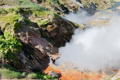 Steaming geothermal field with hot springs and mineral deposits on rocky slopes in Geyser Valley, Kamchatka Krai, Russia, showcasing volcanic activity and nature