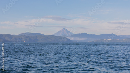 Fényképezés Wide view across Avacha Bay with calm blue water, distant volcanic peak and laye